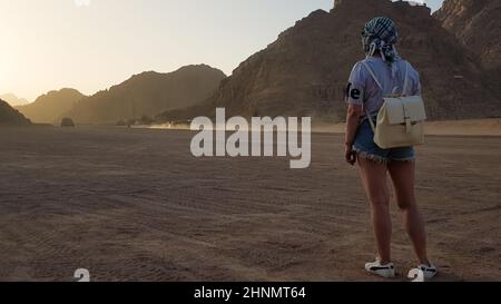 Egypt, Sharm El Sheikh - October 10, 2019. Back view. Portrait of a lonely woman watching a beautiful sunset in the mountains in Egypt. Young girl in the desert. Stock Photo