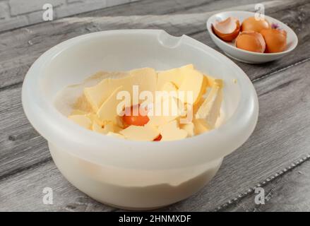 Plastic bowl with butter, egg yolk and flour to be mixed. Cake preparation Stock Photo