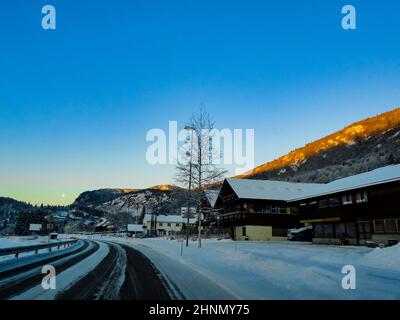 Driving at sunrise through mountains and village in Norway. Stock Photo