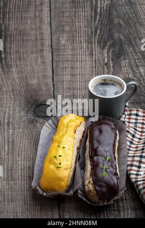Glazed  eclairs with a cup of coffee on wooden table Stock Photo