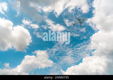 Commercial airline flying on blue sky and white cumulus clouds. Under view airplane flying. Passenger plane travel bubble flight. Vacation travel abroad after coronavirus crisis. Air transportation. Stock Photo