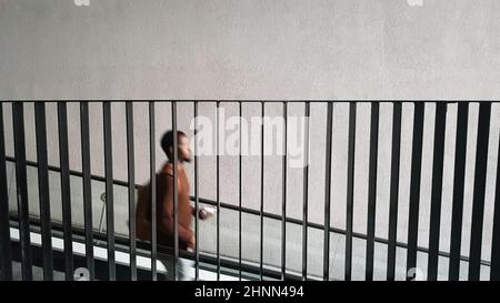 a silhouette of a black man descending the stairs down behind the metal railing. Stock Photo