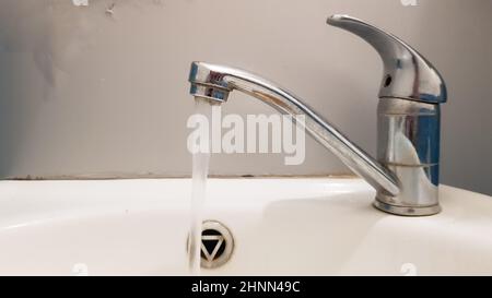 Old and dirty faucet and white ceramic washbasin sink, concept of cleaning, repairing or replacing a bathroom, toilet. Stock Photo