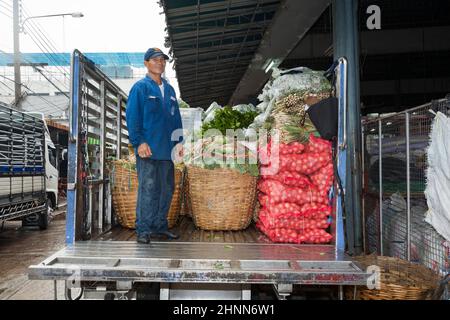 man loads a truck with onions and vegetables at the nightly flower market Pak Klong Thalat in Bangkok Stock Photo