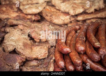 Freshly baked sausages and pork necks prepared on a grill. Stock Photo