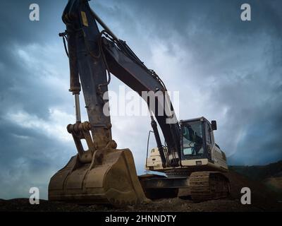 Excavator against dramatic sky Stock Photo