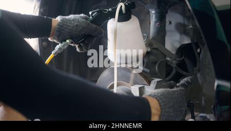 Auto mechanic replacing brake fluid on a vehicle, technician bleed air out of disc brake system in garage workshop, Car repair in a car service Stock Photo