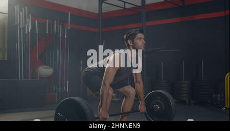 Muscular young Caucasian man exercises working out with lifting weights heavy barbell, Male bodybuilder having workout in gym and fitness club during Stock Photo