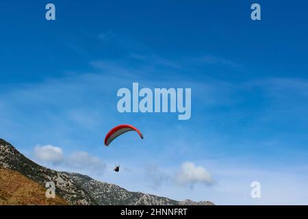 Paraglider silhouette flying over misty mountain valley in beautiful warm sunset colors - sport, active wallpapers full of freedom. Stock Photo
