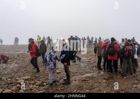 KARPACZ, POLAND - OCTOBER 16, 2021: Tourists at the peak of Sniezka in the Giant Mountains in cloudy weather. Stock Photo