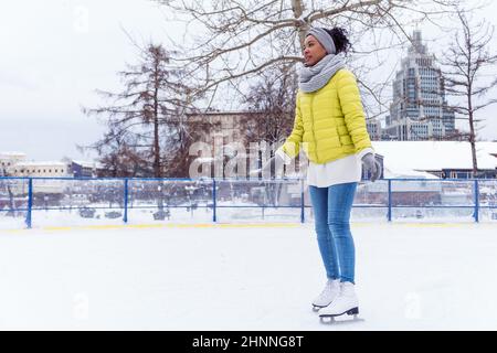 Full lengh portrait of young african american woman skating on ice rink Stock Photo