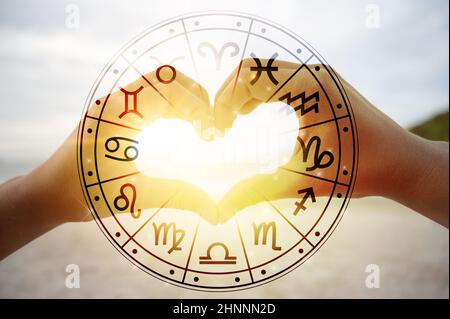 The hands of women and men are the heart shape with the sun light passing through the hands have astrological symbols Stock Photo