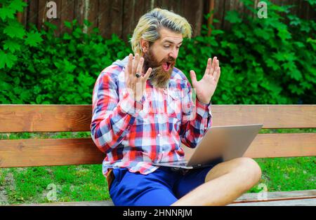 Happy man with laptop at park. Freelance. Money game. Bearded man with computer sitting on bench Stock Photo
