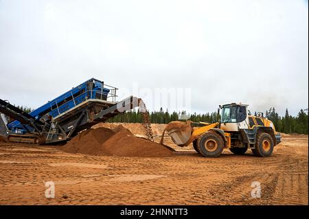 The front loader in the quarry collects a bucket of sand Stock Photo