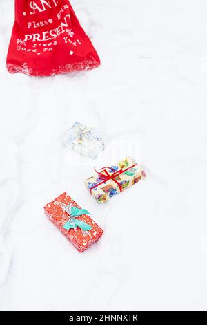 In a snow-covered forest, multicolored bright boxes with gifts are scattered in the snow. Stock Photo