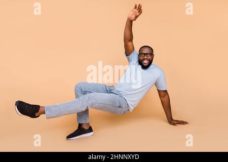 Full length body size view of attractive cheerful guy moving dancing break style isolated over beige pastel color background Stock Photo