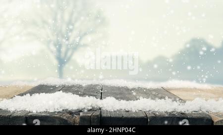 Rustic wooden table with snow and winter landscape, Christmas or seasonal background Stock Photo