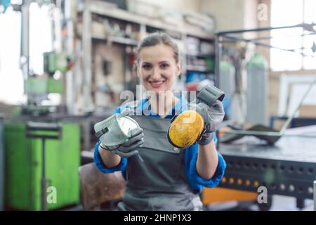 Woman worker in metal factory showing protective workwear, goggles, and ear protection Stock Photo