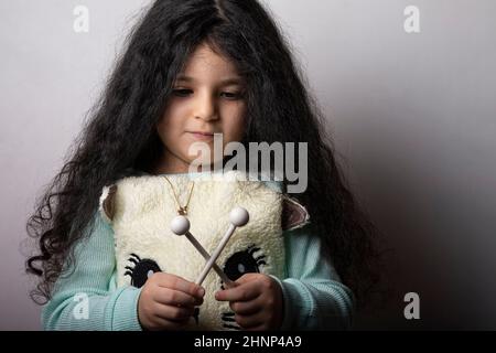 Little girl portrait with xylophone sticks in hand looking down Stock Photo