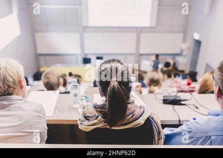 Students listening to lecture and making notes. Professor giving presentation in lecture hall at university Stock Photo