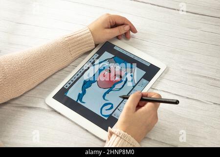 Young creative designer holding stylus pen drawing on screen of digital tablet on wooden desk with copy space, modern digital art top view Stock Photo