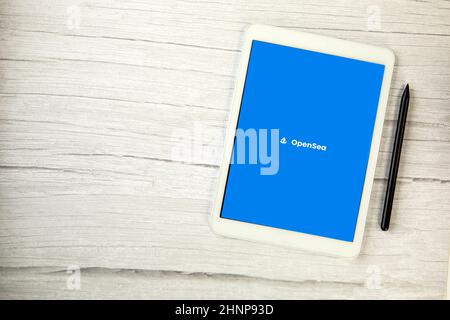 The Netherlands, December 2021 Opensea app on white digital tablet on wooden table with copy space, market place for non-fungible tokens NFT digital art Stock Photo