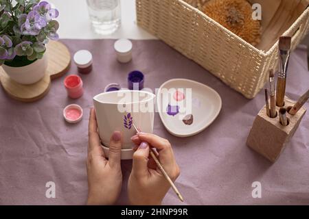 Womens hands paint a flower ceramic pot Stock Photo