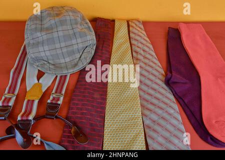 Man garments. Clothing concept for men. Colorful socks, ties, braces and checked flat cap on claret background. Classical concept of men garments. Close-up Stock Photo