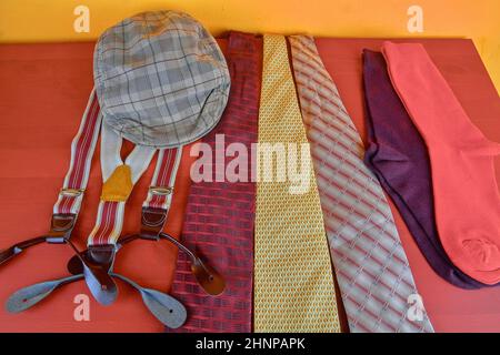 Man garments. Clothing concept for men. Colorful socks, ties, braces and checked flat cap on claret background. Classical concept of men garments. Close-up Stock Photo