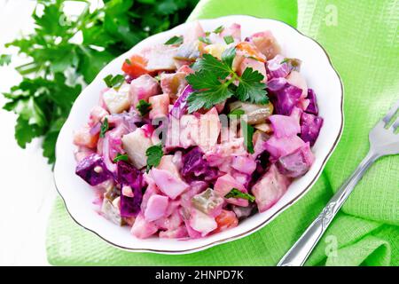 Finnish Rosoli salad with herring, beetroot, potatoes, pickled or pickled cucumbers, carrots, onions and eggs, dressed with mayonnaise in a bowl on wh Stock Photo
