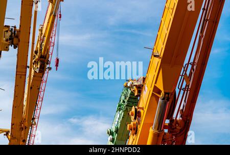 Selective focus on crawler crane against blue sky. Real estate industry. Red crawler crane use reel lift up equipment in construction site. Crane for rent. Crane dealership for construction business. Stock Photo