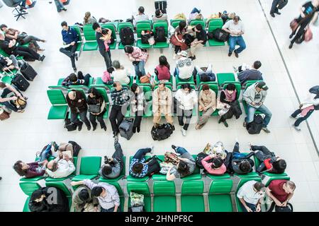 people wait on benches for the departure of their flight at Suvarnabhumi International Airport Stock Photo