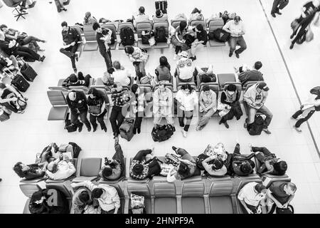people wait on benches for the departure of their flight at Suvarnabhumi International Airport Stock Photo