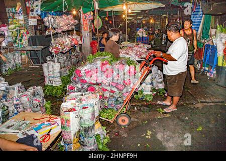 people sell fresh roses at night at the flower market Pak klong Talat in chinatown of Bangkok Stock Photo