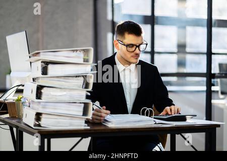 Accountant With Folders Paper Stack Doing Invoice Audit Stock Photo