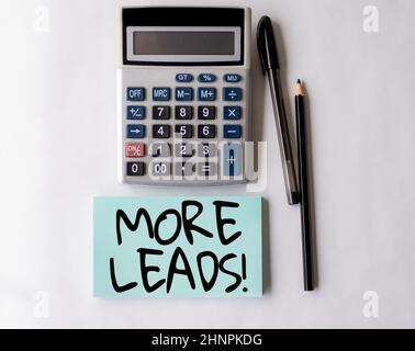 Text sign showing More Leads, Word Written on initiation consumer interest enquiry into products or services Blank Open Spiral Notebook With A Calcula Stock Photo