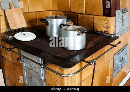 Vintage kitchen stove with aluminium pots and other utensils Stock Photo