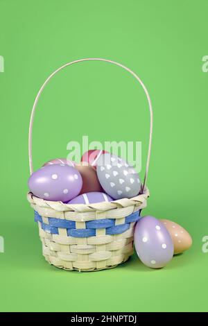 Small easter basket with colorful eggs on green background Stock Photo