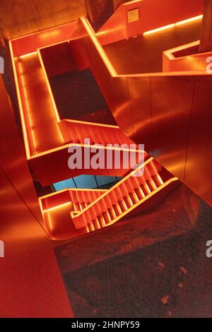 nterior view of beautiful orange illuminated remarkable staircase is located at the entrance of Ruhr museum at Zeche Zollverein, Zollverein Coal Mine Industrial Complex. Stock Photo