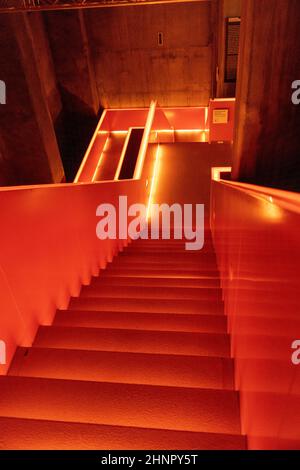 nterior view of beautiful orange illuminated remarkable staircase is located at the entrance of Ruhr museum at Zeche Zollverein, Zollverein Coal Mine Industrial Complex. Stock Photo