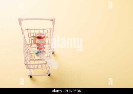 Shopping cart with vaccine vials bottles and syringes for vaccination against coronavirus Stock Photo