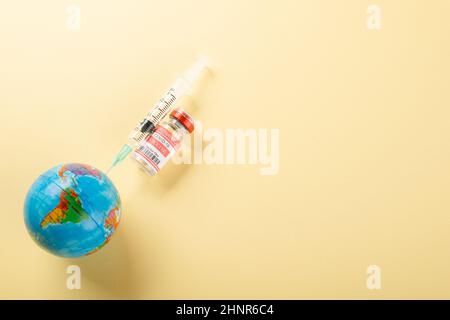 Vaccine vials bottles, syringes for vaccination against coronavirus and globe Stock Photo