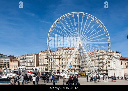 people enjoy big ferris wheel against a blue sky in Marseilles Stock Photo