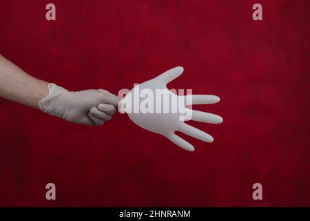 Hand holds inflated medical glove on a red background Stock Photo