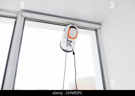 Robot window cleaner work on dirty window. Cleaning the house with smart devices. Automatic vacuum robots for cleaning windows, an assistant for the Stock Photo