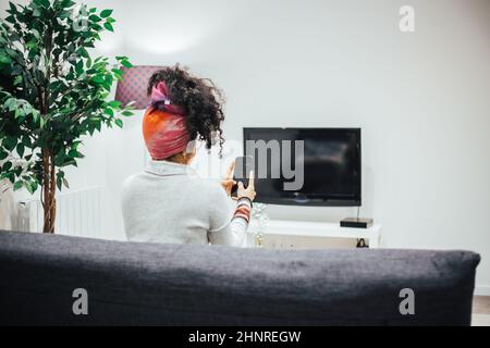 Afro woman using her cell phone in comfort of her home Stock Photo