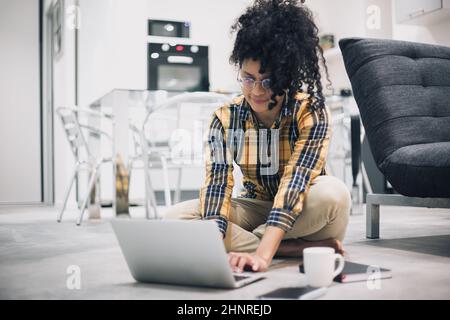Afro woman working drinking coffee sitting on floor of her house Stock Photo