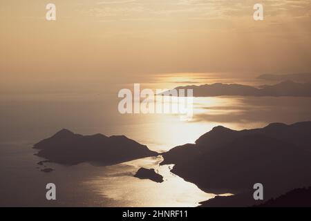 beautiful aerial panorama from the Babadag peak of high mountains rising up over the Mediterranean sea at sunset near Oludeniz Blue Lagoon coast in Tu Stock Photo