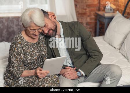 caucasian grandmother got her new technological gadget from her middle-aged son on Grandparent's Day. High quality photo Stock Photo