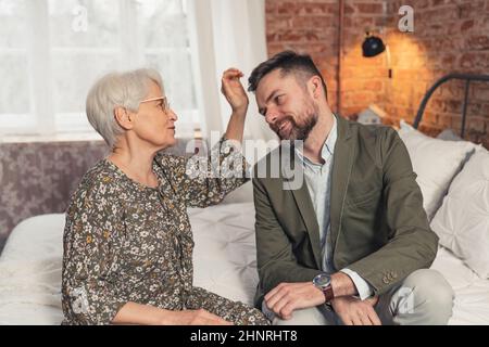 elderly retired caucasian lady petting her son's brown hair celebrating Mother's Day. High quality photo Stock Photo